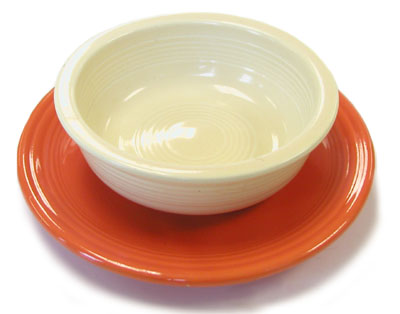 Two pieces of Fiestaware: A fiesta red saucer and an ivory bowl.