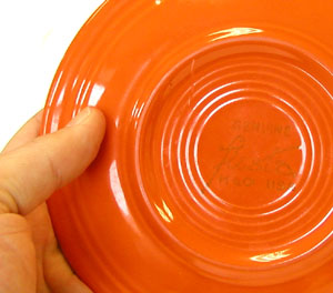 A Fiestaware saucer in Fiesta red with the Fiesta inscription on the back.