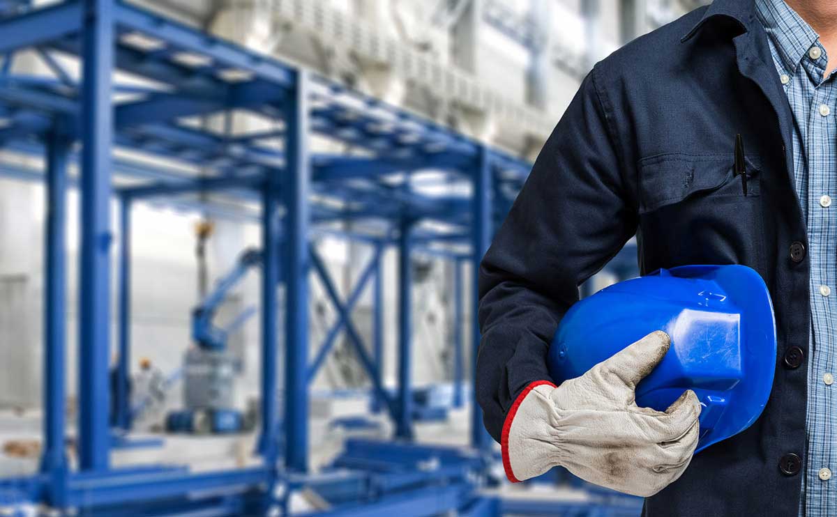 A worker holds a hard hat in a warehouse setting
