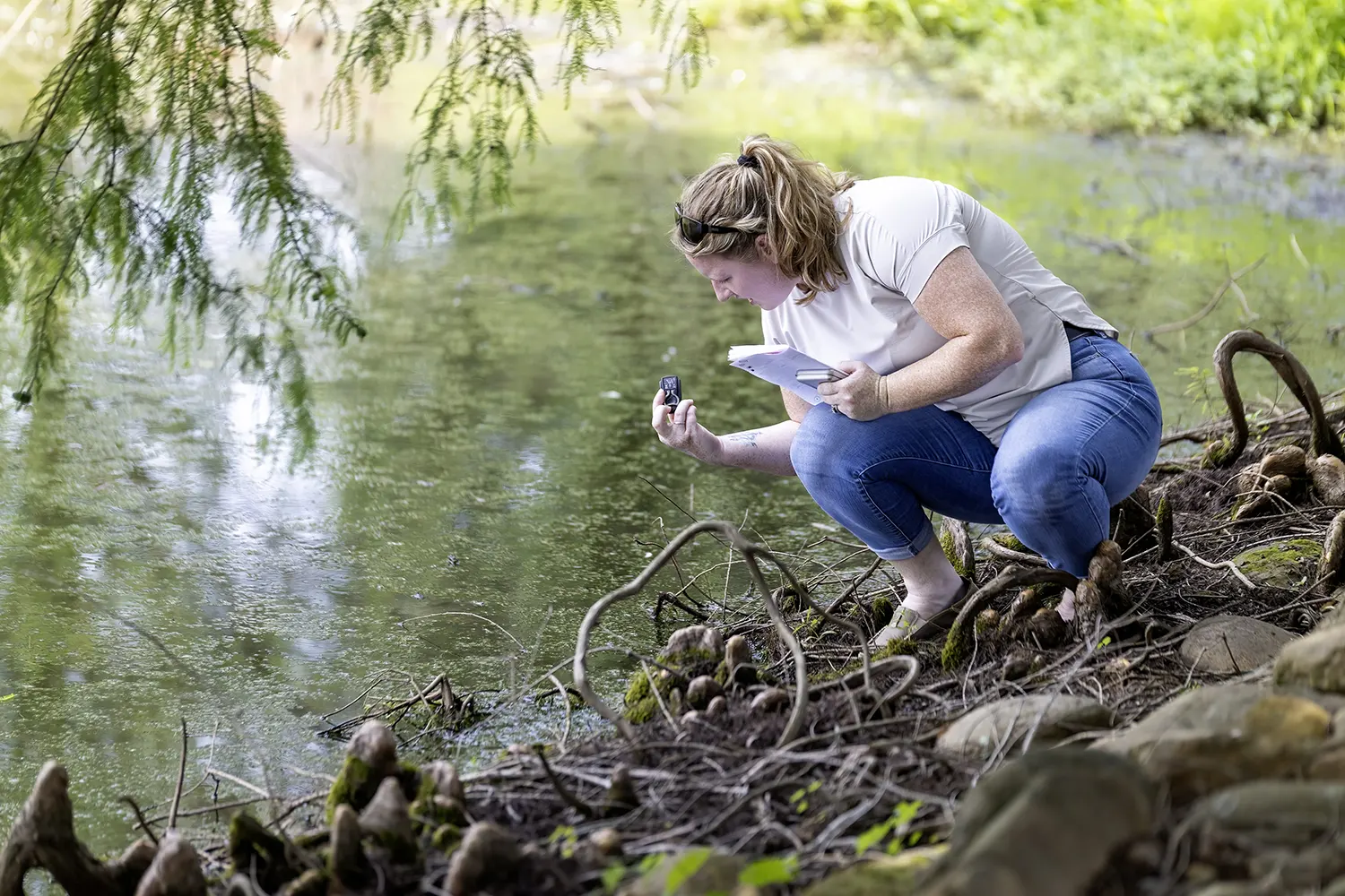 A K-12 educator collects a water sample during the Taking Teaching Outdoors professional development academy hosted by ORAU