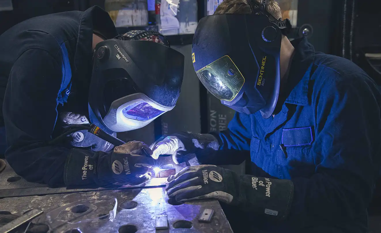 Two welders work on a project in a factory