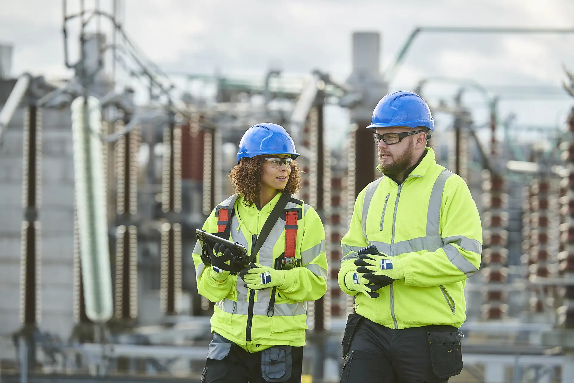 two adults in safety gear at an outdoor plant
